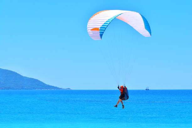 istock Paragliding. Paraglider landing on a blue sea background. 1154920508