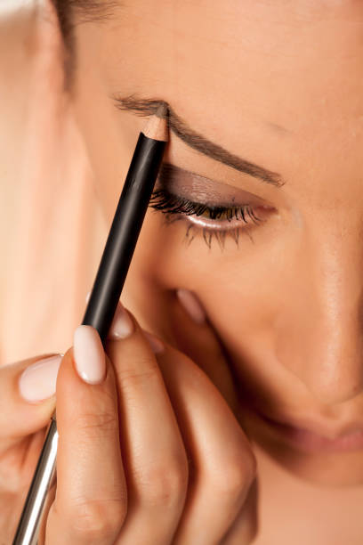 istock Young woman contouring her eyebrows with pencil on white background 1154922574