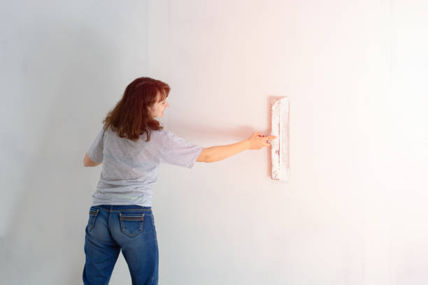 istock woman putty a wall with a spatula. professions. diy 1154923154