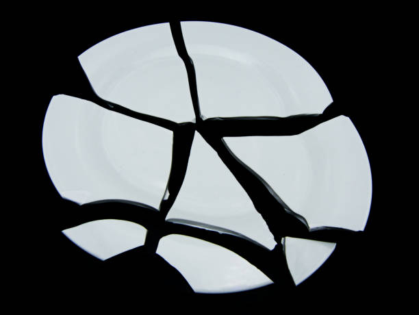 istock Broken porcelain white plate on a black backgroundA studio shot 1154923839