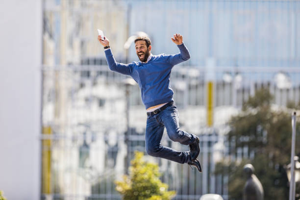 Cheerful mid adult businessman jumping of joy on the street. Copy space.