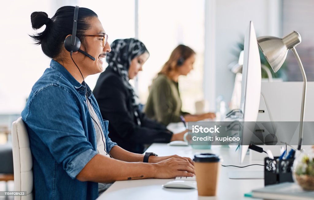 We pride ourselves in delivering quality customer services Shot of a group of young call centre agents wearing headsets and working on their computers in an office Call Center Stock Photo
