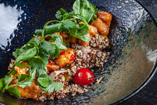 Close up on fresh Quinoa salad with chicken tempura, cherry tomatoes, basil and sweet and sour sauce. Copy space. Concept of healthy food. Lunch or tasty appetizer. Summer menu. Homemade salad bowl