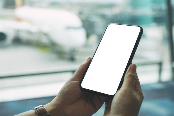 istock a woman's hands holding and using black mobile phone with blank screen while sitting in the airport 1154929783