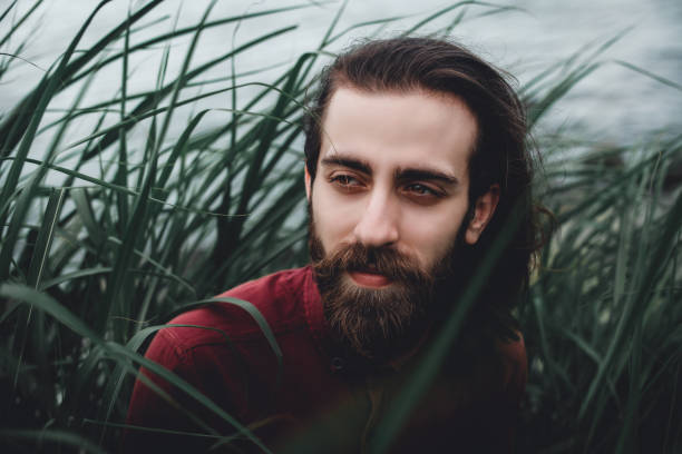 istock Young bearded handsome guy sitting in grasses 1154930281
