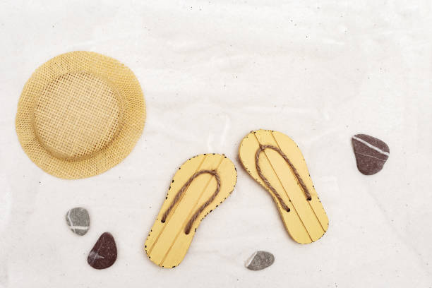 istock Beach sandals and straw hat on light sand background. Beach accessories. Flat lay. Copy space. 1154932427