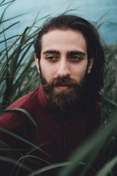 istock Young bearded handsome guy sitting in grasses 1154932613