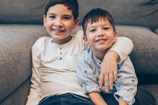 Portrait of Two smiling boys, brothers sitting on the floor at home and looking at camera