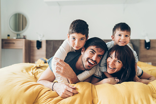 Portrait of happy family with two children lying in bed and smiling