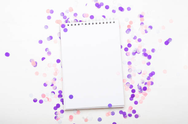 Notepad with confetti and colored pencils on the white background. Concept school supplies. Copy space, top view, flat lay
