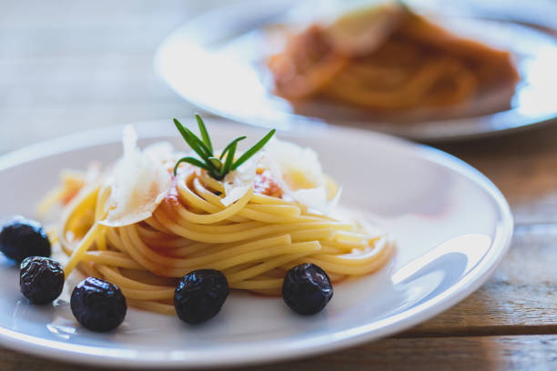 Spaghetti with tomato sauce, hard cheese and black olives on plate