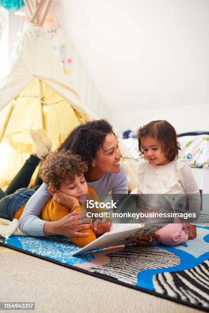 Alleinerziehende Mutter Lesen Mit Sohn Und Tochter In Den Im Schlafzimmer Zu Hause Stockfoto und mehr Bilder von Familie