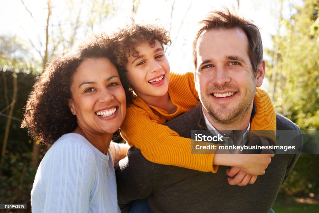 Outdoor Portrait Of Smiling Family In Garden At Home Against Flaring Sun Family Stock Photo