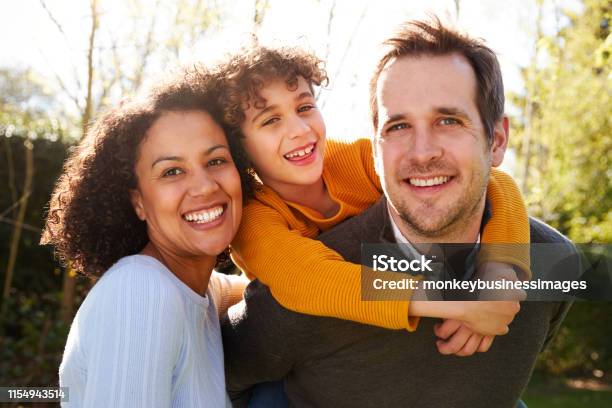 Outdoor Portrait Of Smiling Family In Garden At Home Against Flaring Sun Stock Photo - Download Image Now