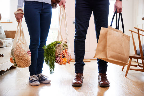 從購物旅行回家的夫婦關閉攜帶食品在塑膠免費袋 - 環保袋 個照片及圖片檔