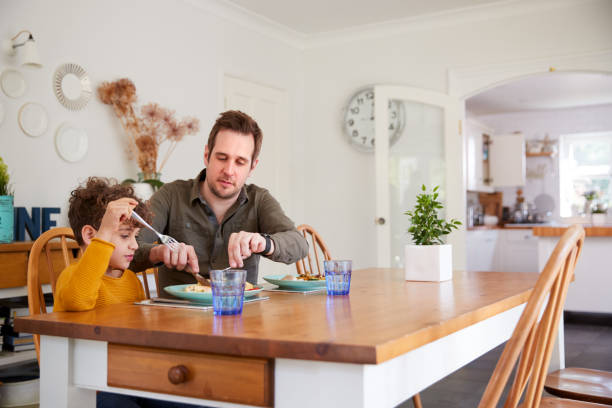 istock Single Father Sitting At Table Eating Meal With Son In Kitchen At Home 1154944199