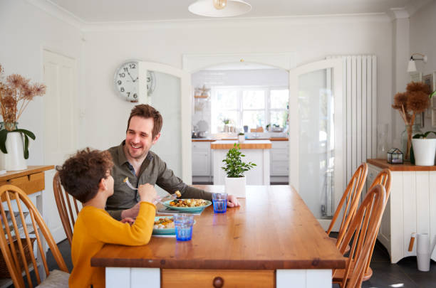 istock Single Father Sitting At Table Eating Meal With Son In Kitchen At Home 1154944297