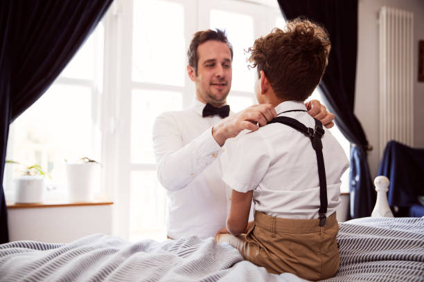 Father And Son Wearing Matching Outfits Getting Ready For Wedding At Home Father And Son Wearing Matching Outfits Getting Ready For Wedding At Home ring bearer stock pictures, royalty-free photos & images