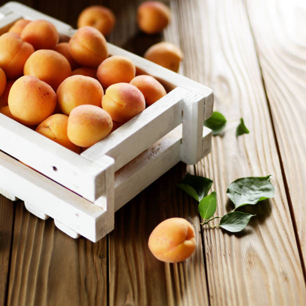 istock White wooden crate with apricots on table 1154945476