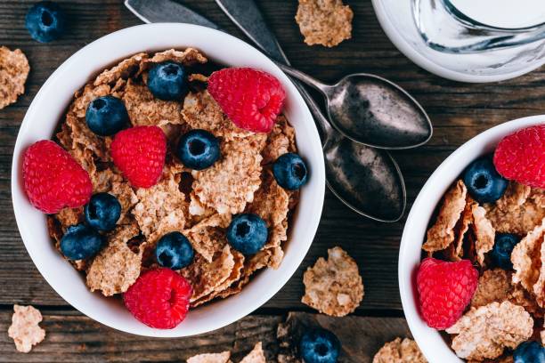 ganzes getreidegetreide mit frischen heidelbeeren und himbeeren zum frühstück. - bran cereal stock-fotos und bilder