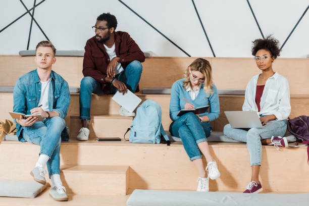 istock four multicultural students with notebooks and laptop studying in lecture hall 1154947881
