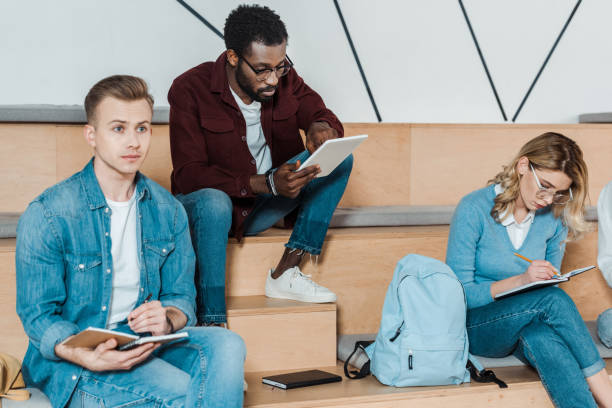 istock three multiethnic students with notebooks and digital tablet studying in lecture hall 1154947935