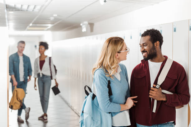 istock smiling multiethnic students looking at each other in corridor in college 1154948005