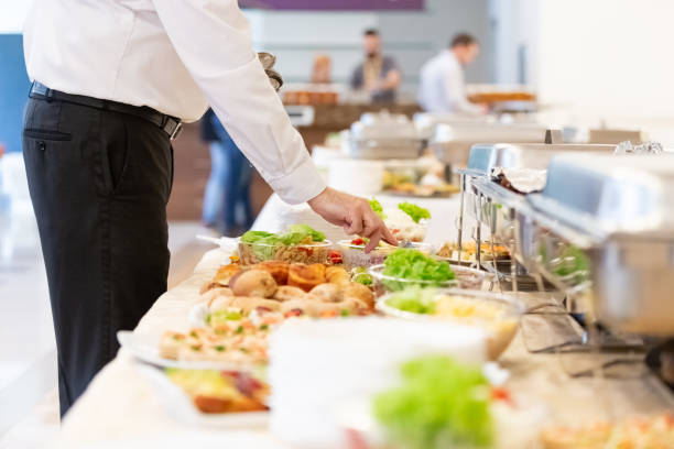 Close up of waiter hand preparing putting spoon in salad on buffet table. Waiter preparing buffet table with canapes and salads with vegetables. food service occupation food and drink industry party buffet stock pictures, royalty-free photos & images