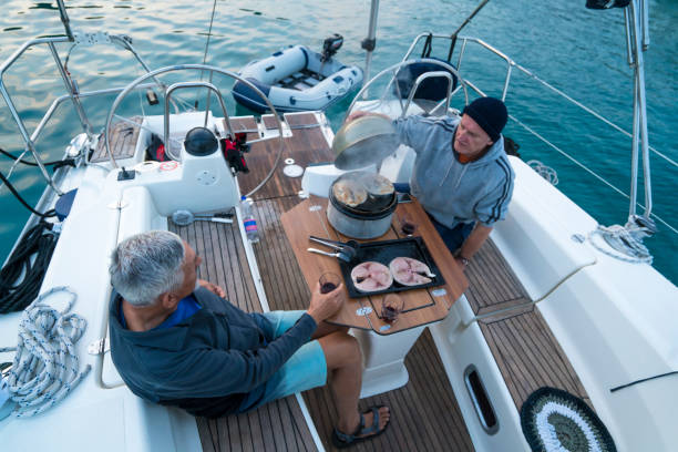 istock Two men drinking wine while grilling tuna on sailing boat 1154950060