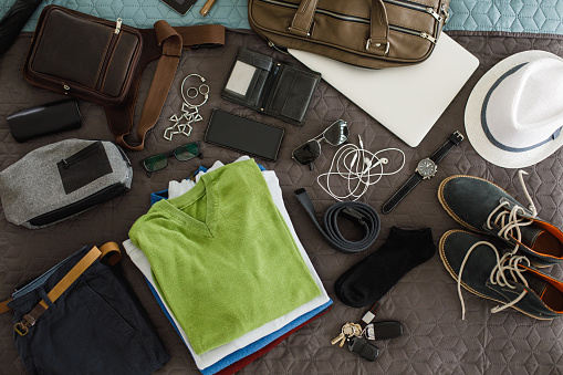 Packing male accessories for travel, devices, clothes, wallet, sunglasses, jewelry, technology.