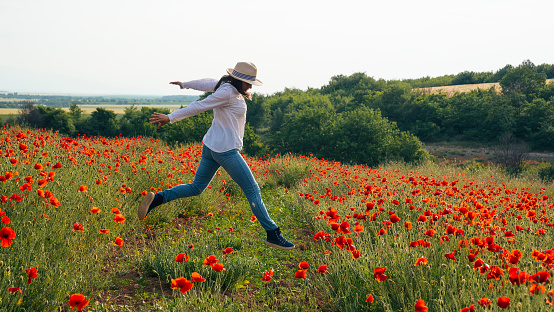 Cheerful lady enjoying nature in romantic outdoor atmosphere, promenade in a wild flowers field, carefree and relaxed.