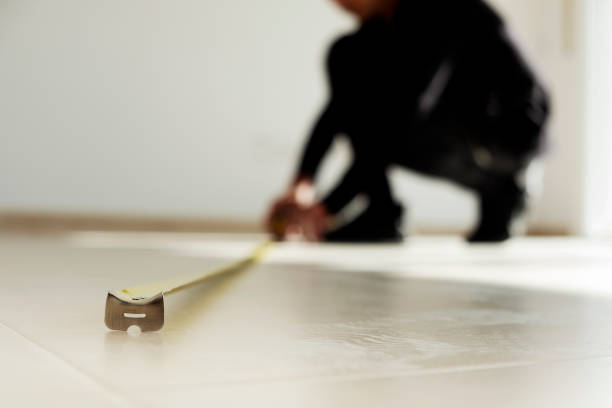 man using a measuring tape on a tiled floor closeup of a young caucasian man using a measuring tape on a beige tiled floor instrument of measurement stock pictures, royalty-free photos & images