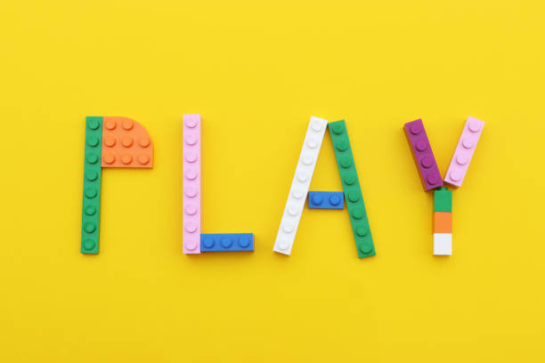 the word play formed by multi colored toy bricks on a yellow background