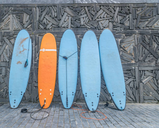 istock Four blue and one orange surfboard leaning against a stone wall. 1154951889