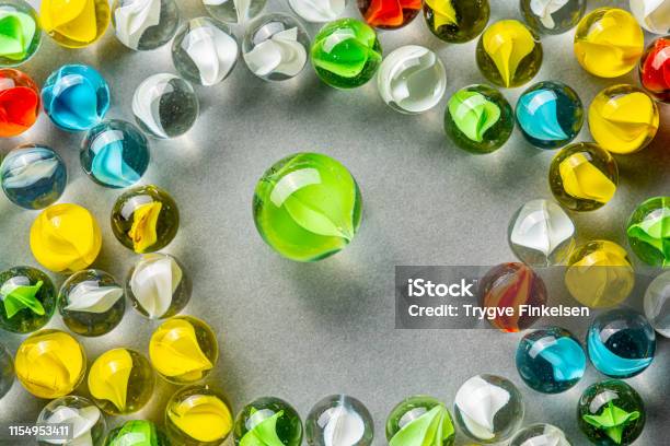 A Big Green Glass Marble Between Yellow Green Blue And Red Marbles On A  Table Stock Photo - Download Image Now - iStock