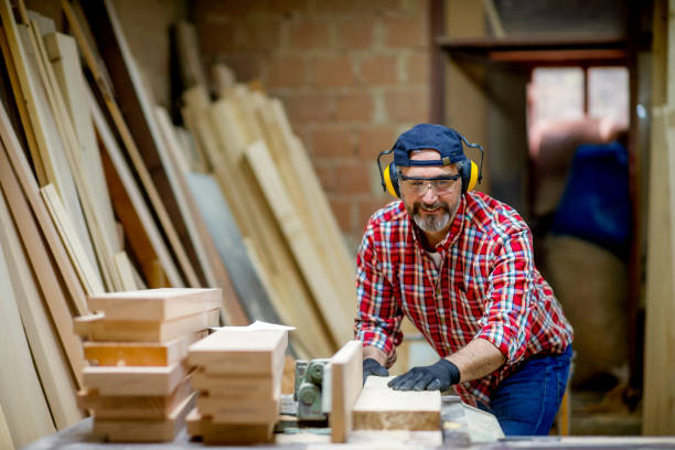 istock Carpenter sawing a board with a table saw 1154956448