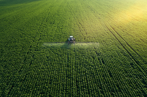 Cuidando de la cosecha. Vista aérea de un tractor que fertilizar un campo agrícola cultivado. photo