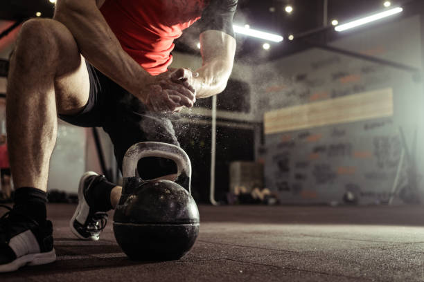 Sports background. Young athlete getting ready for gym training. Powerlifter hand in talc preparing to exersising with the kettlebell. stock photo