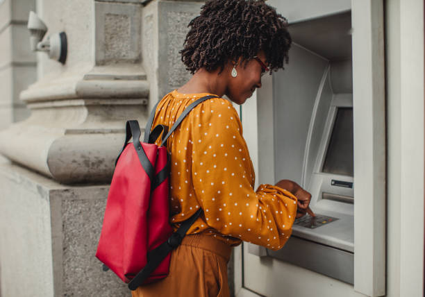 woman making a cash withdrawal at an atm - atm imagens e fotografias de stock
