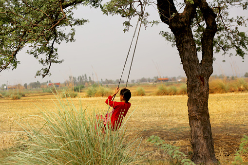 Elementary age child swinging on rope outdoor in nature.