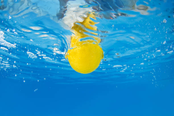 Lemon splashing in blue water. Underwater shot