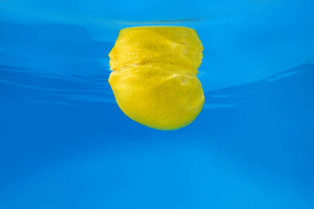 Lemon splashing in blue water. Underwater shot