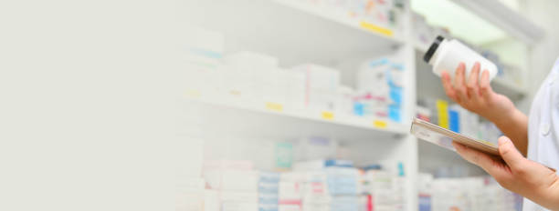 istock Pharmacist holding medicine bottle and computer tablet in pharmacy 1154964159