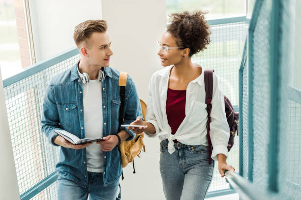 istock smiling multiethnic students with notebook and smartphone looking at each other in university 1154970974