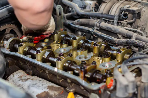 Photo of Disassembled the internal combustion engine, the hand of the repairman cleans the cylinder head