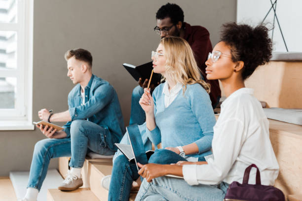 istock multicultural students with notebooks and laptop in lecture hall 1154971138