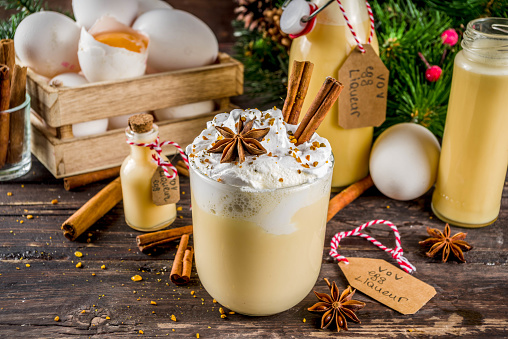 Christmas Bombardino Livigno cocktail with egg liqueur VOV and rum. With cinnamon, spices. Wooden background with christmas decorations, copy space