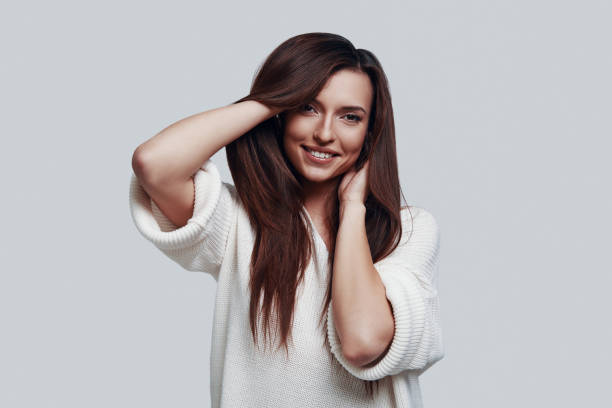 istock Cute beauty. Attractive young woman looking at camera and smiling while standing against grey background 1154972893