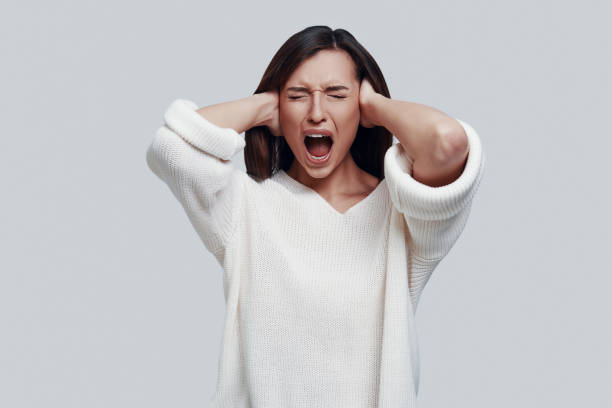 istock Frustration. Displeased young woman keeping eyes closed and shouting while standing against grey background 1154974110