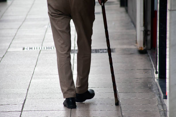 Rear view of senior man's legs, walking  with a walking cane, disabled. Asturias, Spain.